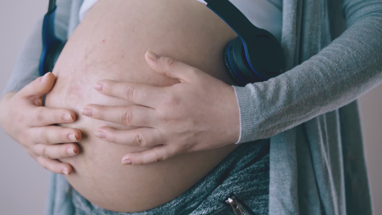 donna incinta ascolta musica con il bambino usando le cuffie