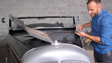 man working on a vintage classic car in a garage
