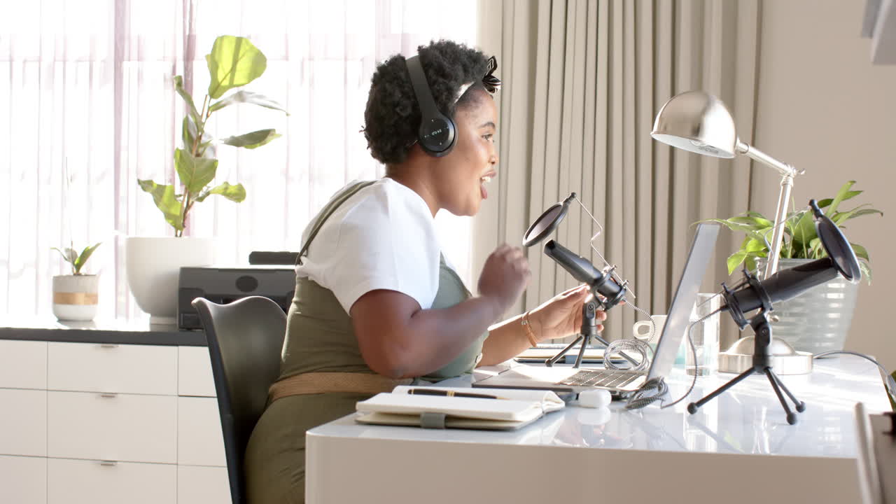 Afroamerikansk kvinde optager en podcast i et lyst hjemmekontor derhjemme