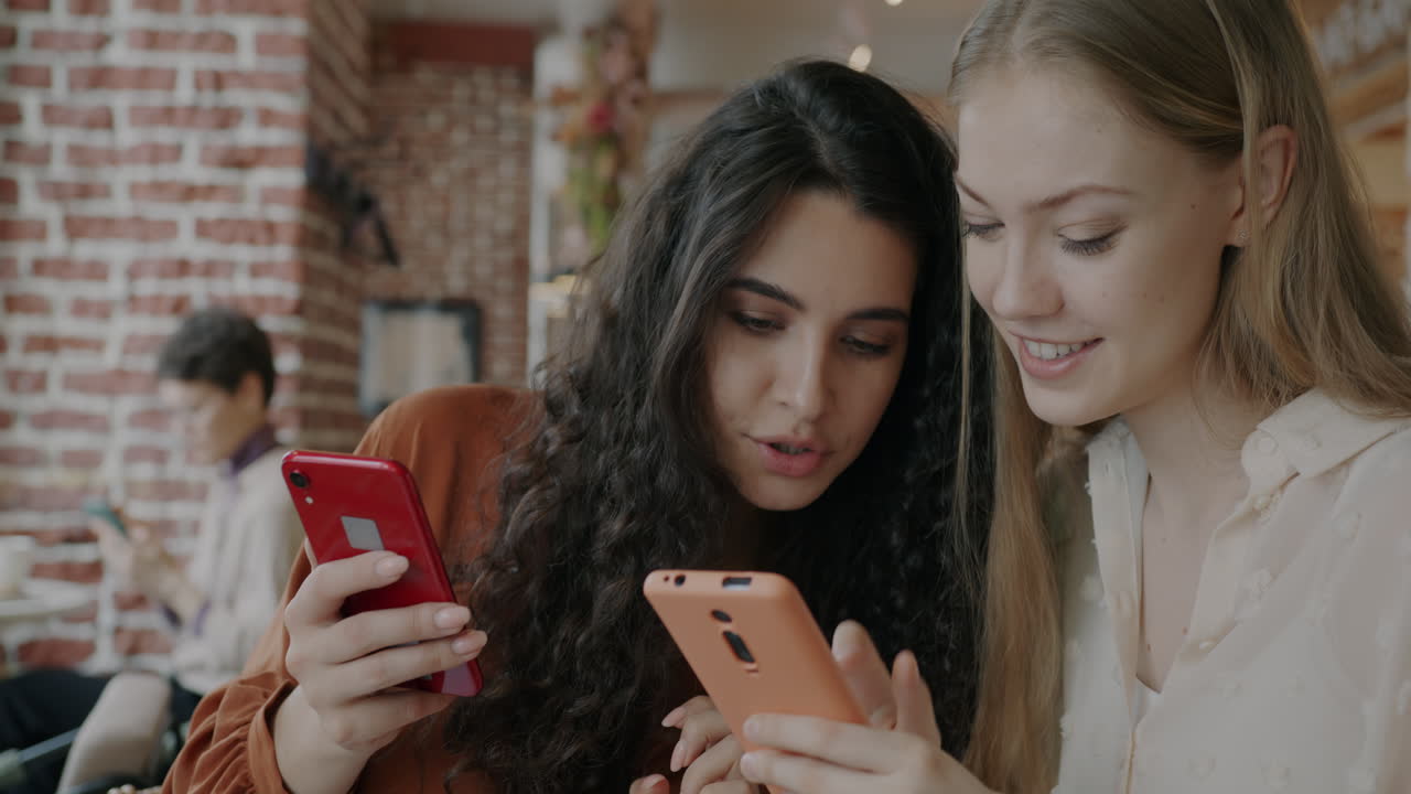 Two Women Friends Using Smartphones in a Cafe