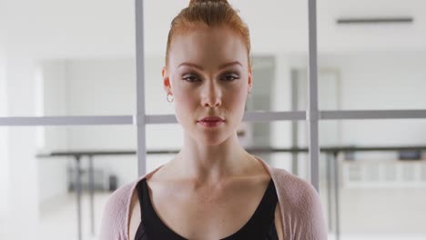bailarina de ballet caucásica de pie en un estudio brillante y mirando a la cámara