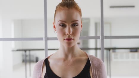 caucasian female ballet dancer standing a bright studio and looking at camera