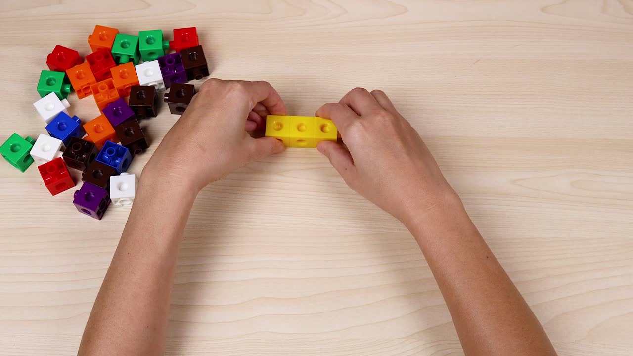 manos montando cubos amarillos en una mesa de madera