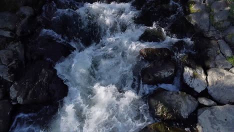 Fluss-Mit-Steinen-Und-Bäumen-Am-Rande,-Filmischer-Drohnenschuss