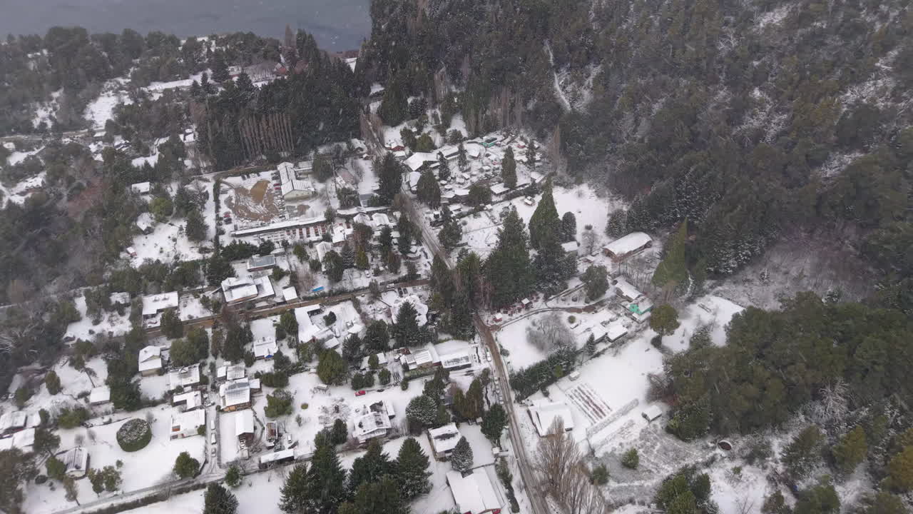 Drone gliding under heavy snowfall in Colonia Suiza, a town in San Carlos de Bariloche at the foot of Cerro López, covered in snow from above during a heavy winter storm in the Argentine Andes