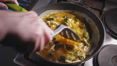 cooking and stirring asparagus and eggs in a pan for breakfast