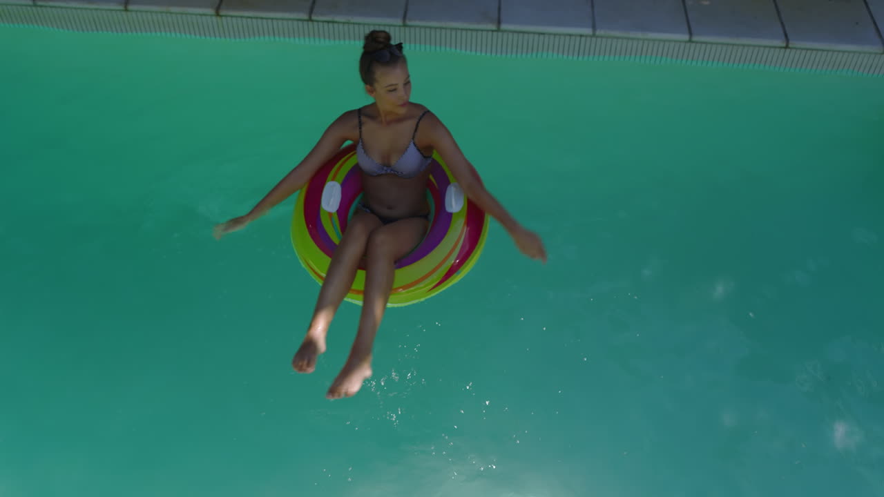 Relaxing in pool, woman floating on colorful inflatable ring, enjoying summer day, copy space