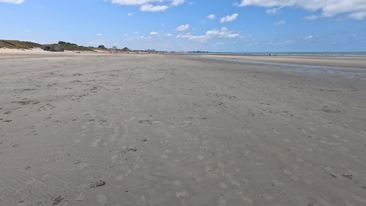 Smooth forward camera movement over a wide, empty sandy beach in Dunkirk, France