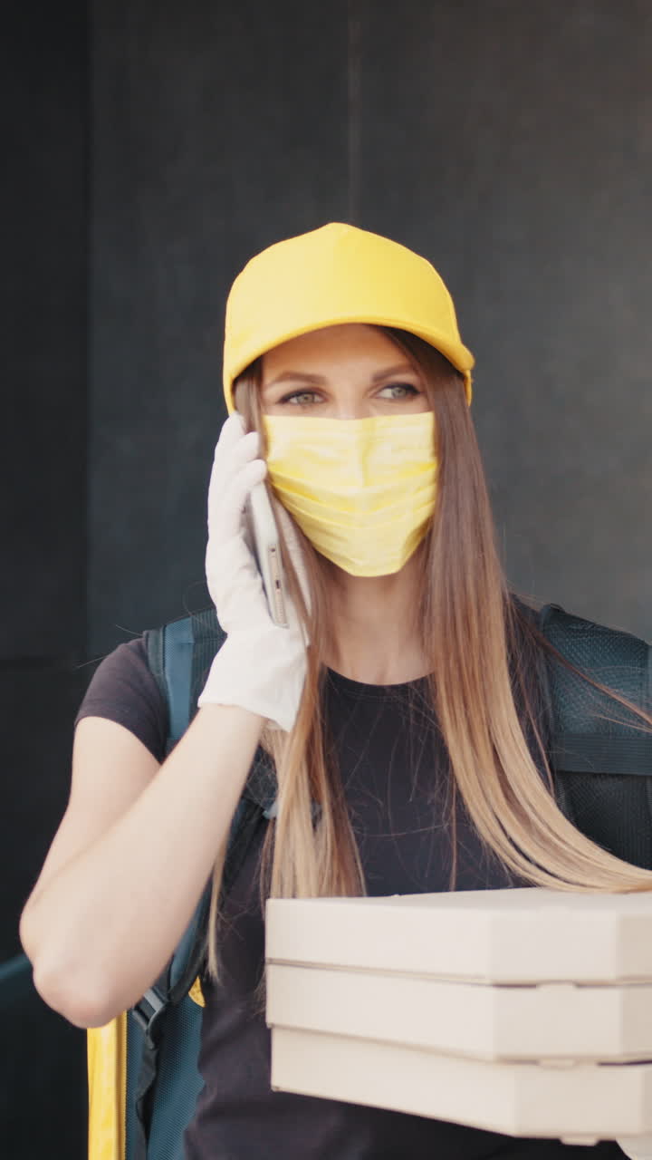 Delivery person wearing a mask and gloves talking on the phone