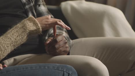 Close-Up-Of-Loving-Young-Couple-Relaxing-At-Home-Sitting-On-Sofa-Holding-Hands-Together