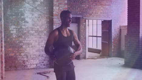 in gym with exposed brick walls, man holding medicine ball exercising