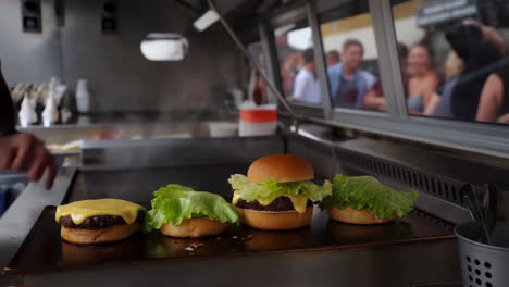 chef assembling cheeseburgers on a hot griddle