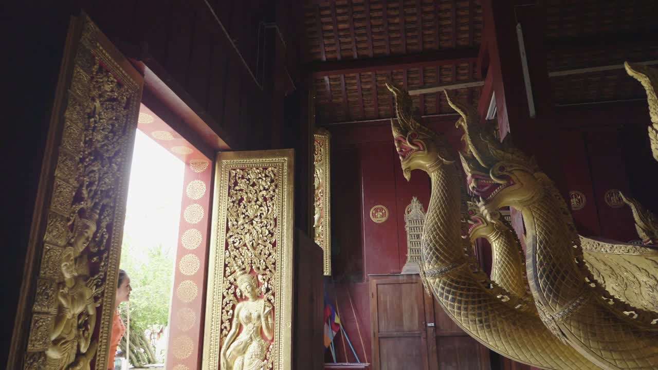 Smuk asiatisk pige går ved Wat Xieng Thong vartegn i Luang Prabang, slowmotion