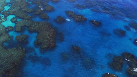 Eine-Drohne-Nimmt-Eine-Luftaufnahme-Eines-Blauen-Lagunenriffs-Auf,-Auf-Dem-Tagsüber-Wellen-Brechen