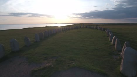 Ancient-Oval-Formed-Rocks-Ales-Stenar-At-The-Summer-Evening-Sunset,-In-South-Sweden-Skåne-Österlen-Kåseberga,-Aerial-Low-Forward