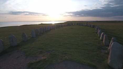 ancient oval formed rocks ales stenar at the summer evening sunset, in south sweden skåne österlen kåseberga, aerial low forward