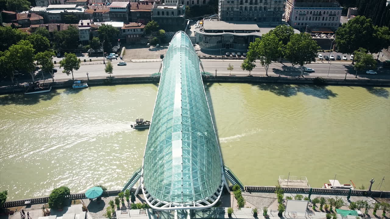 Aerial drone view of Tbilisi, Georgia. Kura river with a modern bridge over it, a lot of greenery, floating boats