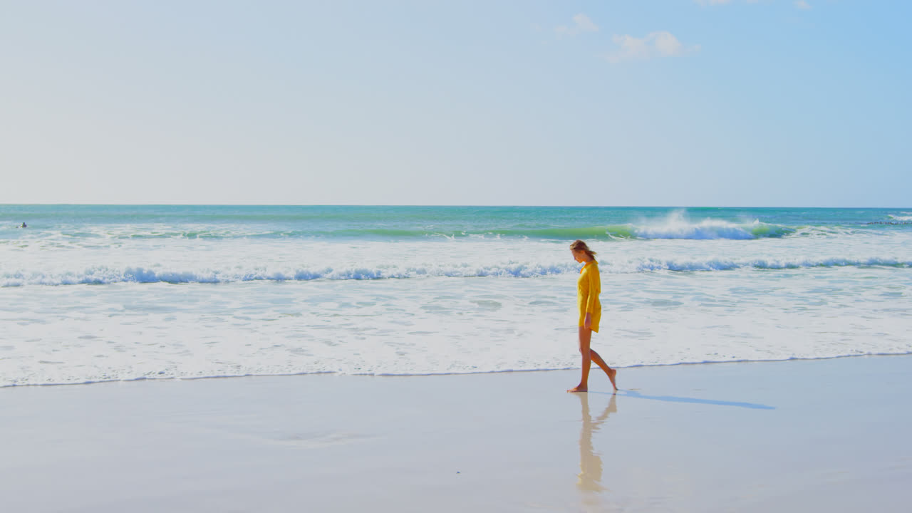 해변에서  ⁇ 는 동안 해변에 물을 뿌리는 젊은 백인 여성의 측면 전망 4k