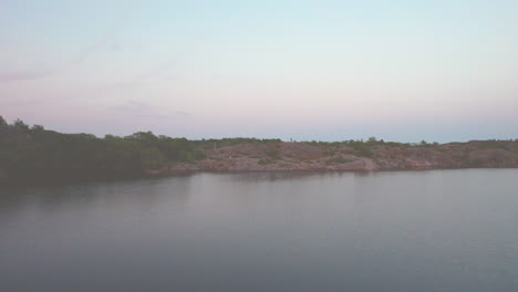 Flying-low-over-a-lake-and-climbing-above-a-natural-harbor