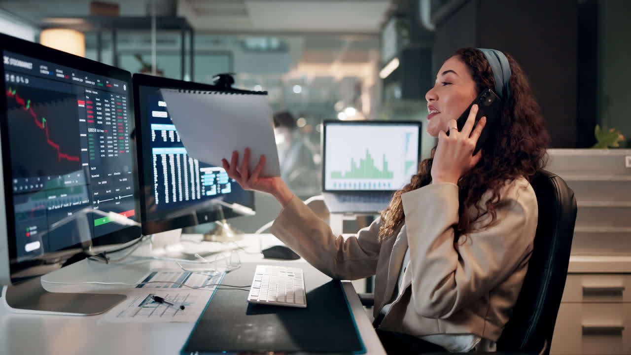 donna d'affari che esamina documenti finanziari mentre fa una telefonata in un ufficio moderno.