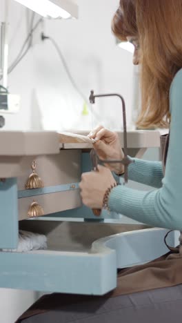 artisan working on jewelry with a saw