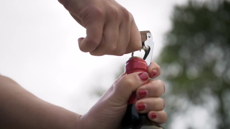 Opening a red wine bottle outdoor´s with two hands and a cork screw