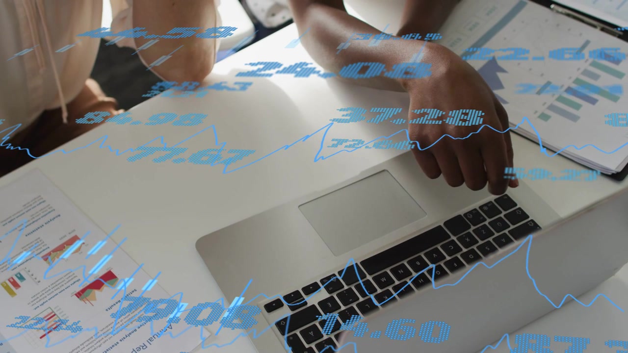 Due donne che esaminano dati finanziari, una che indica e poi preme un tasto del laptop e controlla un overlay blu