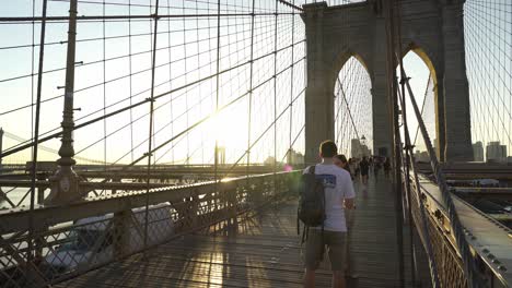couple walking on brooklyn bridge at sunset