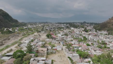 Flying-over-the-houses-of-Panajachel,-Guatemala-with-Lake-Atitlan-in-the-background