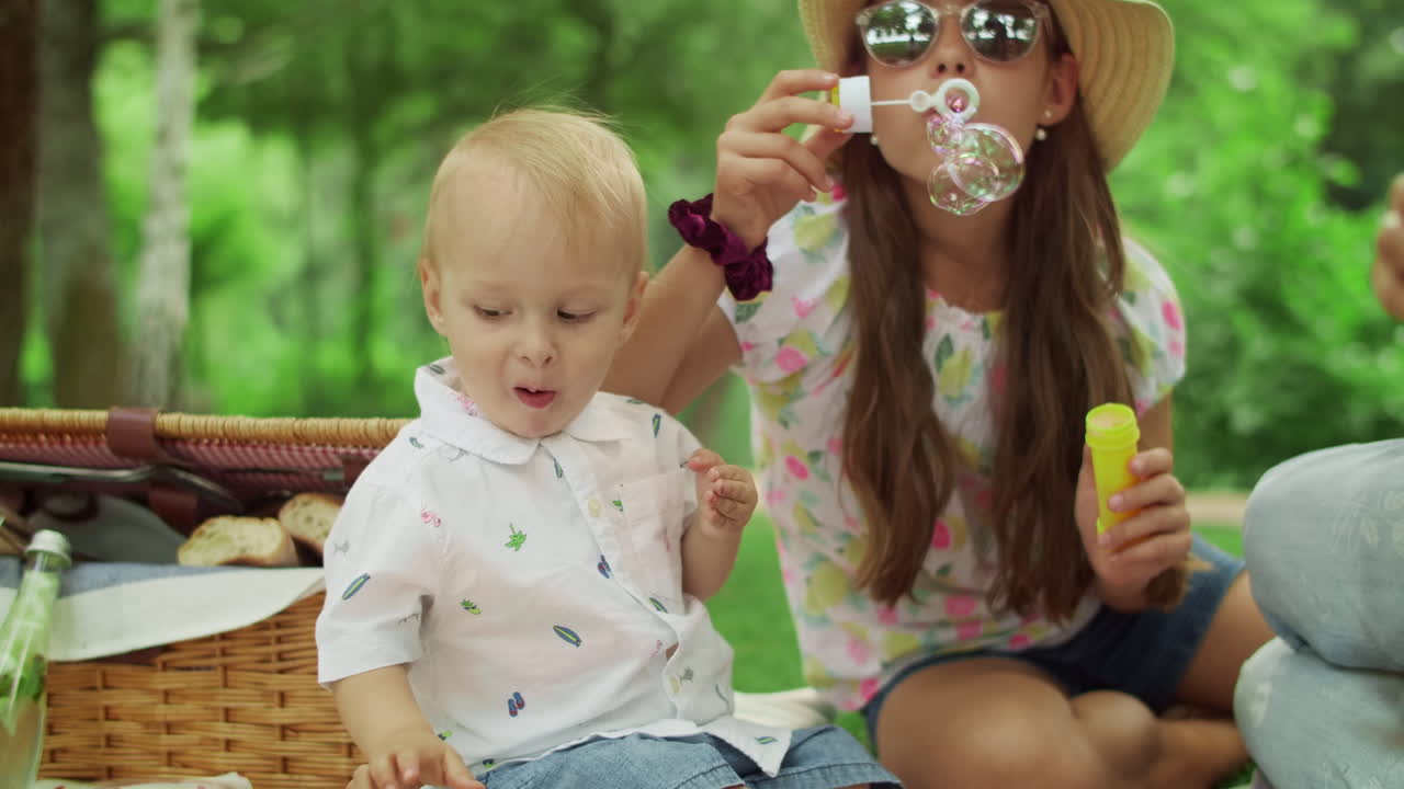 숲에서 피크닉을 하는 체리를 먹고 있는 유아. 공원에서 담요에 앉아 있는 가족
