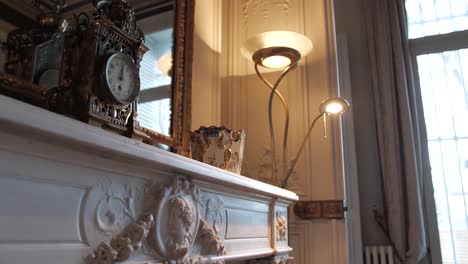 dolly hand-held shot revealing a highly intricate marble fireplace with antique objects as decorations