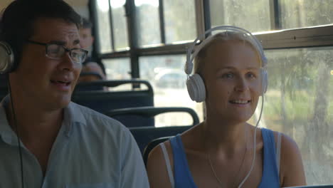 young couple listening to music on headphones during the bus ride they dance to the music man singing