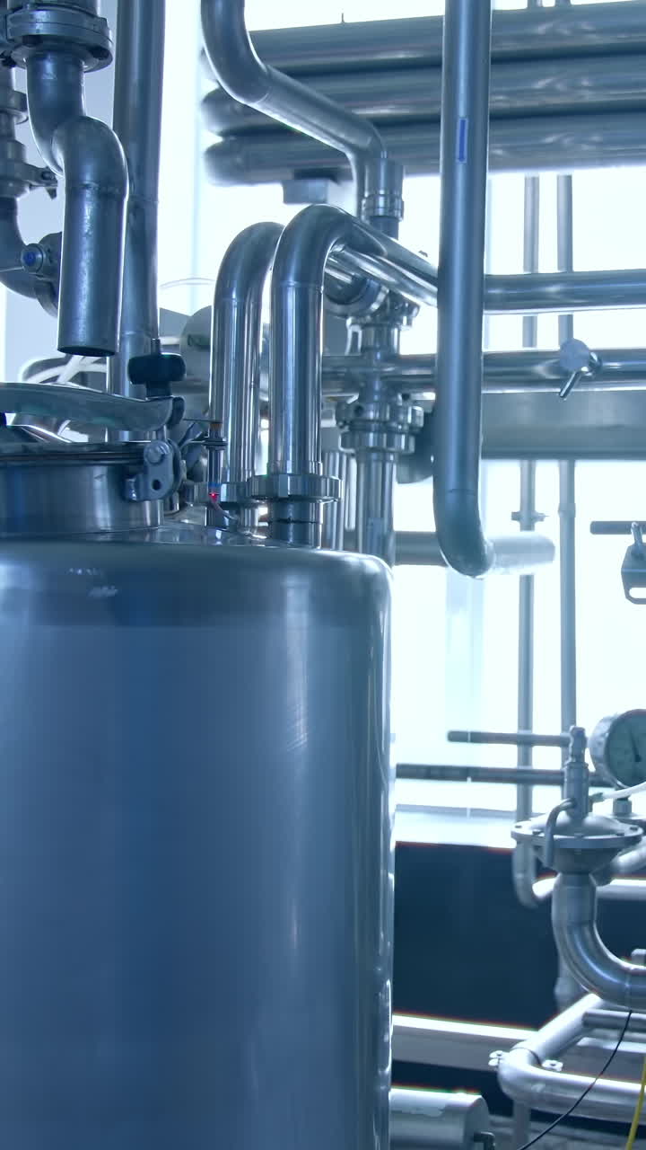 Modern milk factory with stainless tubes. Steel huge diary factory technologies. Vertical video