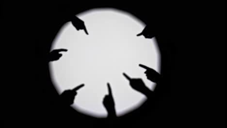 silhouettes of hands pointing towards a bright circle