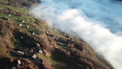 small village on the slope of a mountain range with low hanging clouds of fog in the valley