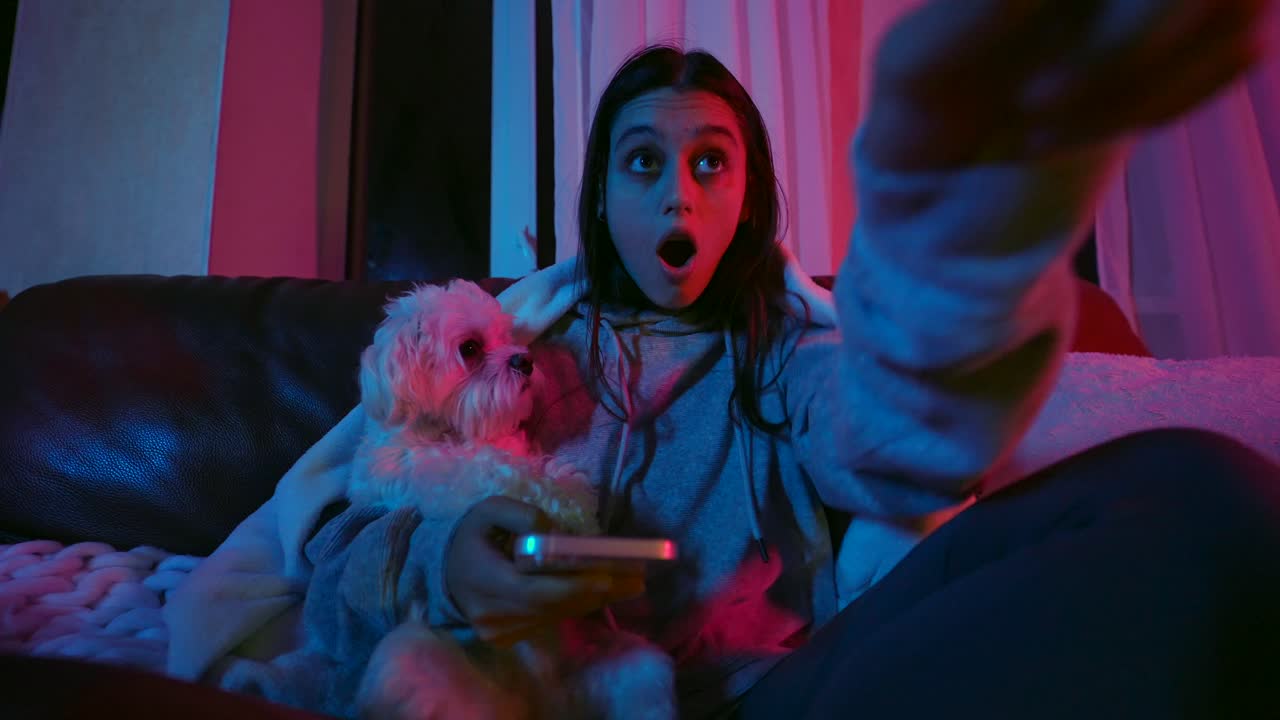 подростковая девушка смотрит телевизор с собакой по ночам.