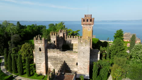 scaliger castle of lazise - medieval fortress in lakeside village with view of lake garda in background. orbiting drone shot