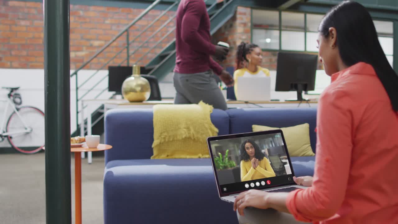 Donna birazziale che usa il laptop per una videochiamata, con un collega di lavoro sullo schermo
