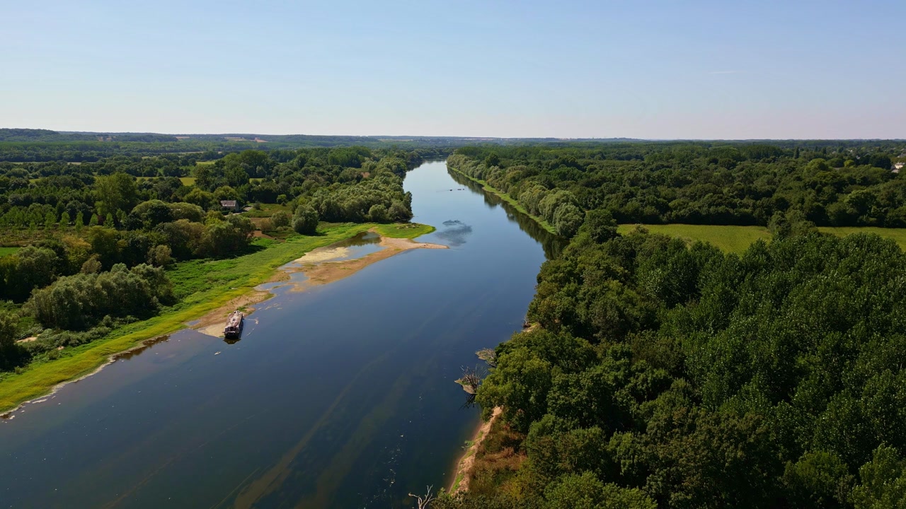 Aerial drone shot over the Vienne River near Chinon, showing sandbanks, surrounding forest, and clear summer weather.