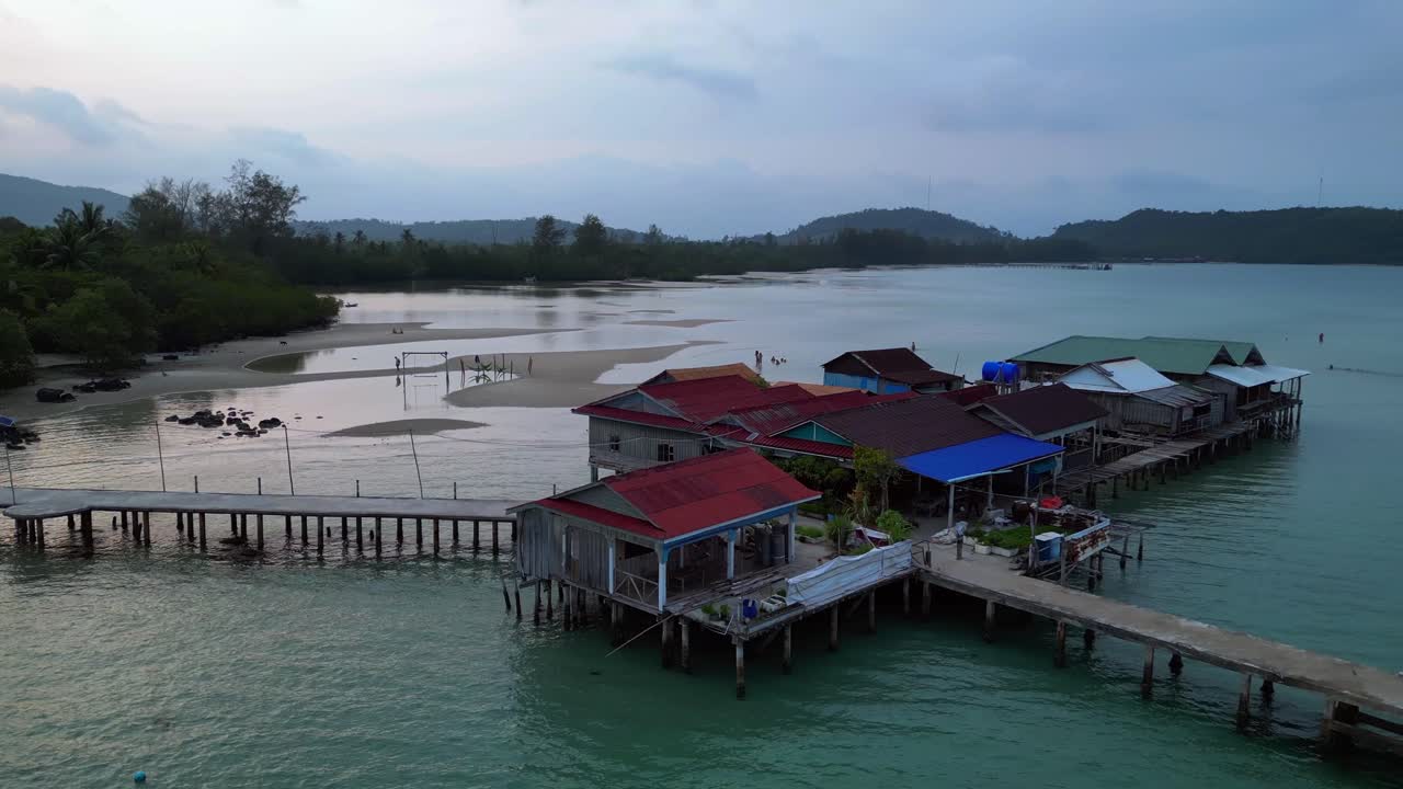 cambodia Koh Rong island, capturing the essence of tropical paradise with its lush palm trees, vibrant turquoise waters, and traditional stilt houses. Beautiful aerial view flight circle drone footage