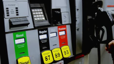 A-young-attractive-brunette-lifts-the-nozzle-off-of-a-gas-pump-and-selects-the-octane-before-turning-to-fuel-up-her-vehicle-on-a-cold-winter-night