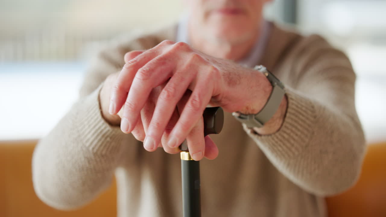 Close Up of Senior Man's Hands Resting on a Walking Stick