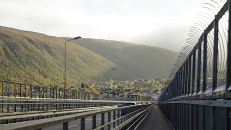 traffic and pedestrian walkway in tromso bridge during autumn in norway with distant mountain scenery