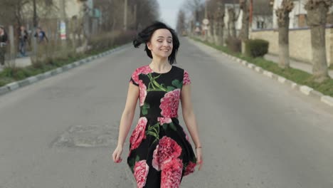 Una-Joven-Atractiva-Con-Un-Vestido-Con-Flores-Corriendo-Por-La-Carretera.