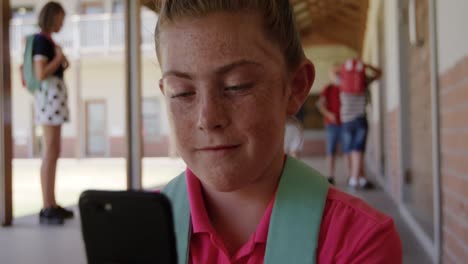 chica usando un teléfono inteligente en el pasillo de la escuela