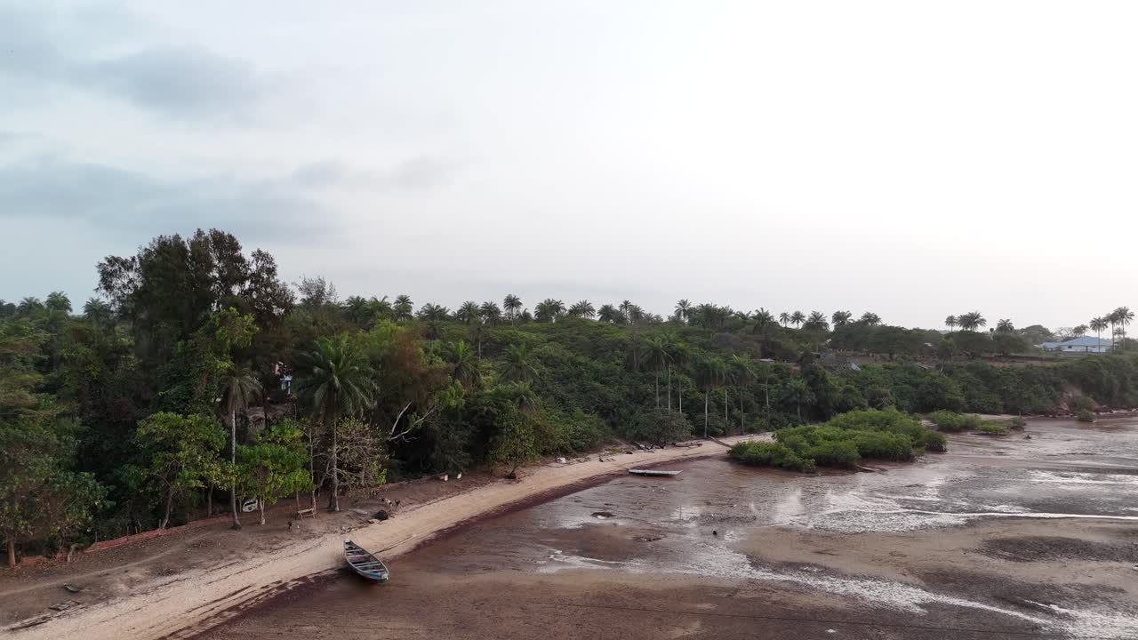 Aerial view of turquoise bay and rocky shore with tropical palm tree beach in Bijagos Islands, Guinea Bissau, west African coastline drone footage