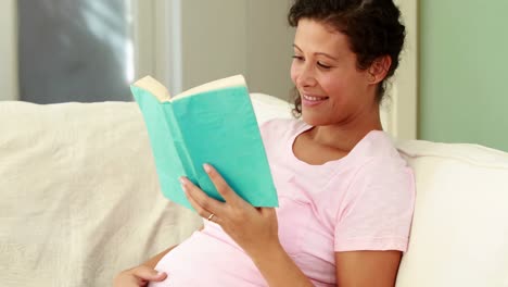 mujer embarazada leyendo en el sofá