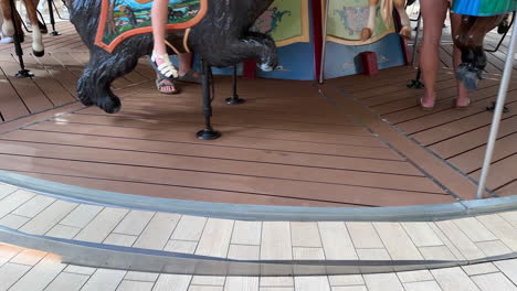 close up, merry-go-round platform spinning, horses and peoples legs