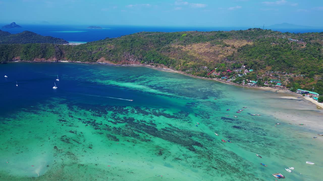 Acqua turchese che circonda un'isola tropicale con vegetazione verde lussureggiante in Thailandia.