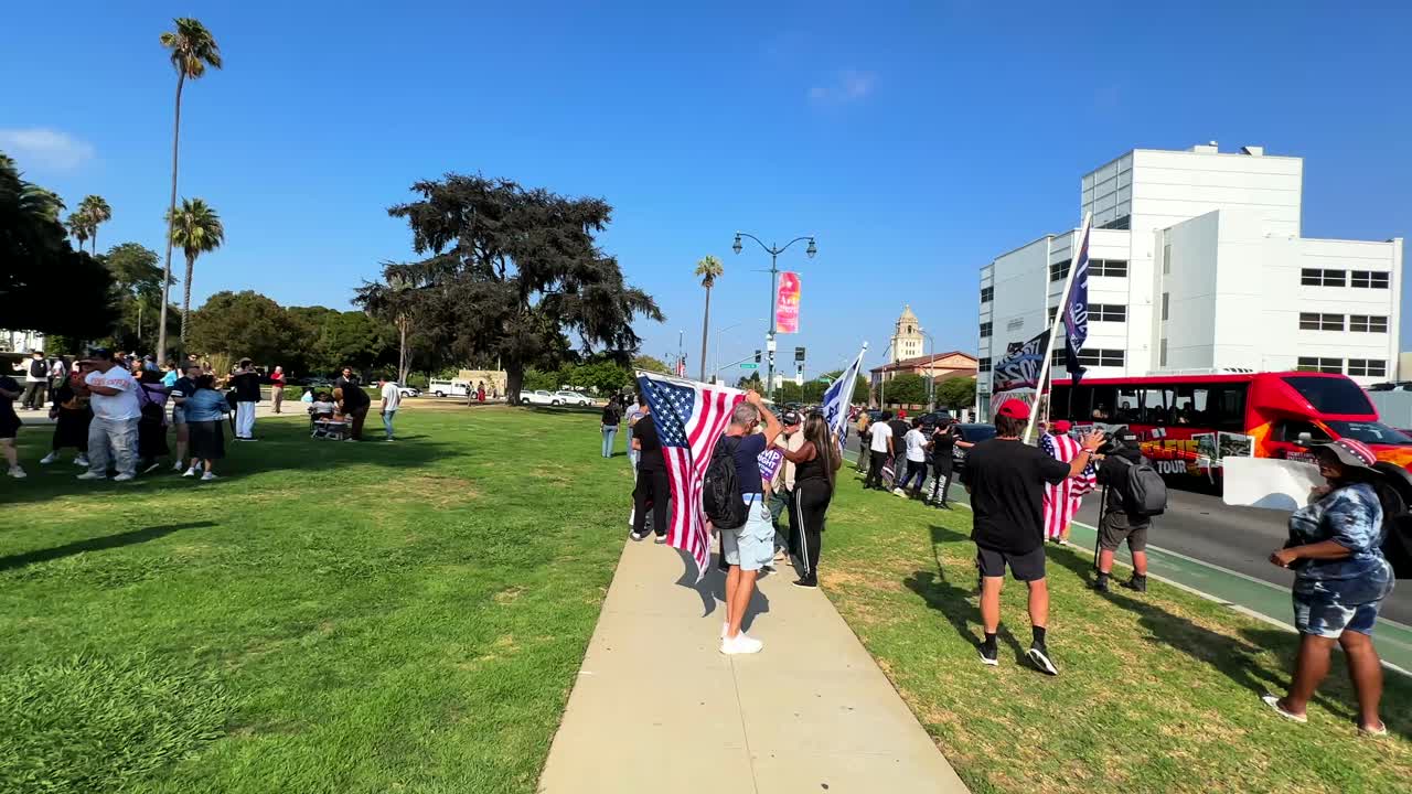 Trump supports in Beverly Hills park with rally flags and banners waving to people in cars passing by